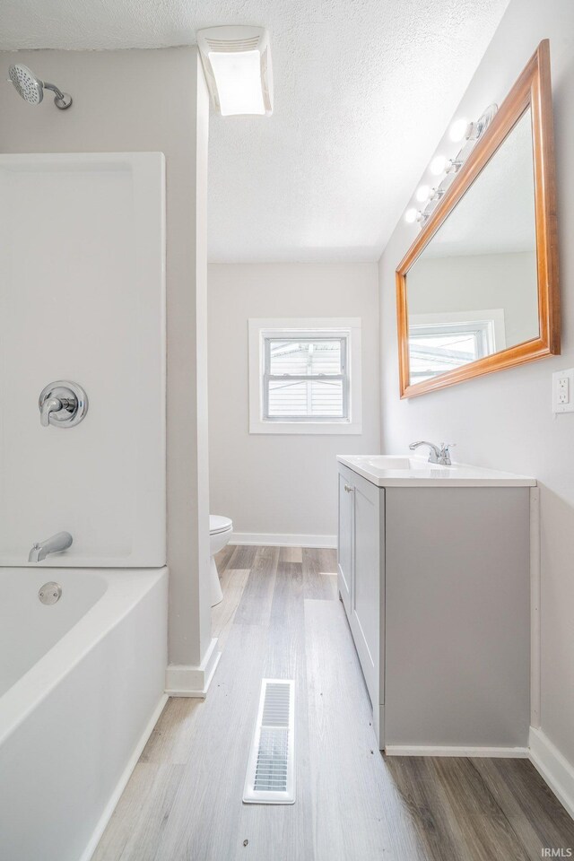 921 Race St, Logansport, IN 46947 - full bath featuring vanity, wood finished floors, shower / bathtub combination, and a textured ceiling