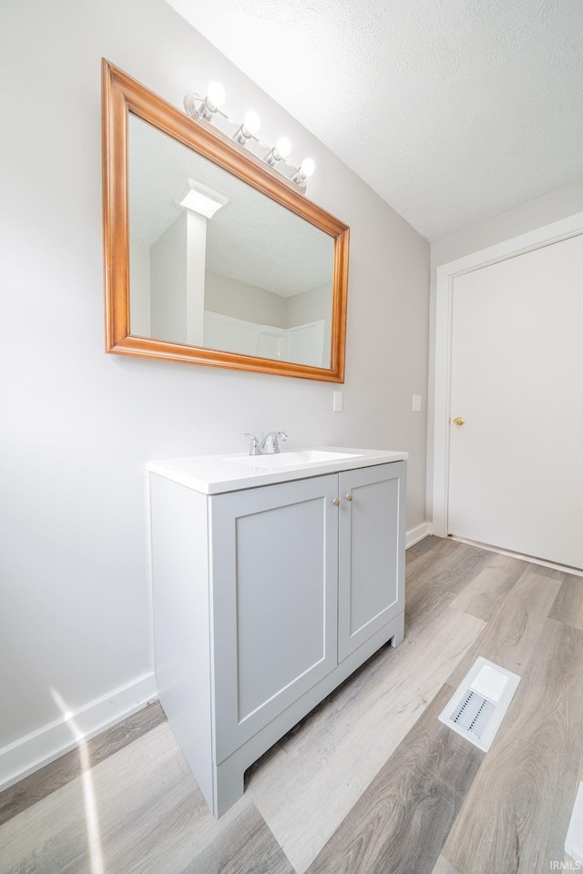 921 Race St, Logansport, IN 46947 - bathroom with wood finished floors, vanity, and a textured ceiling