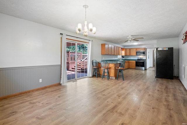 3076 N 450 Rd E, Logansport, IN 46947 - kitchen featuring appliances with stainless steel finishes, a peninsula, a chandelier, light wood-type flooring, and wainscoting