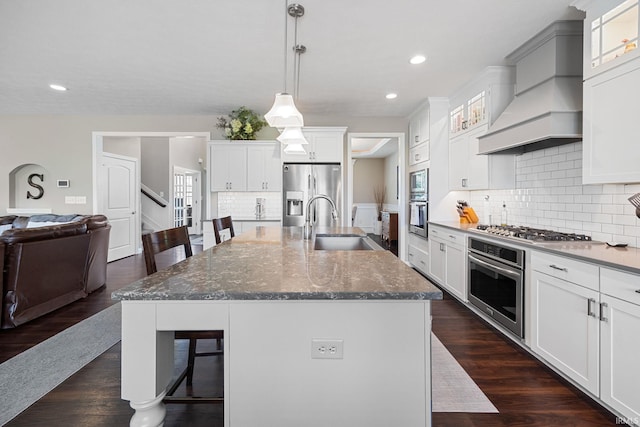 1869 Paloma Ct, Lafayette, IN 47909 - kitchen with appliances with stainless steel finishes, a kitchen bar, decorative backsplash, custom range hood, and a kitchen island with sink