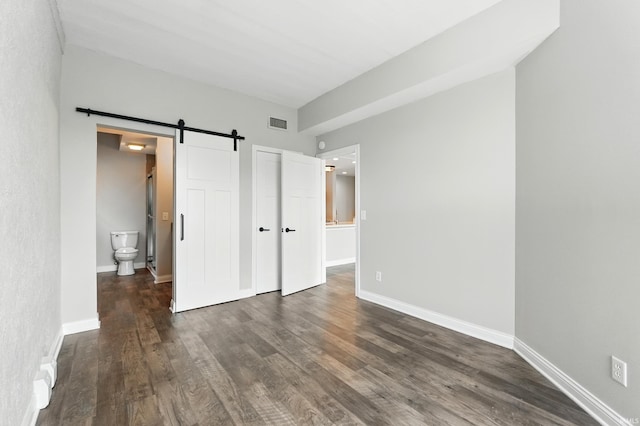 112 W Washington Blvd Unit 329, Fort Wayne, IN 46802 - unfurnished bedroom with a barn door, dark wood-style flooring, and ensuite bathroom