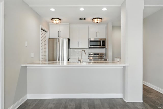 112 W Washington Blvd Unit 329, Fort Wayne, IN 46802 - kitchen with stainless steel appliances, a peninsula, decorative backsplash, dark wood-type flooring, and recessed lighting