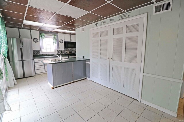 2907 Prairie Ln, Lafayette, IN 47904 - kitchen featuring appliances with stainless steel finishes, a peninsula, dark countertops, a paneled ceiling, and tasteful backsplash
