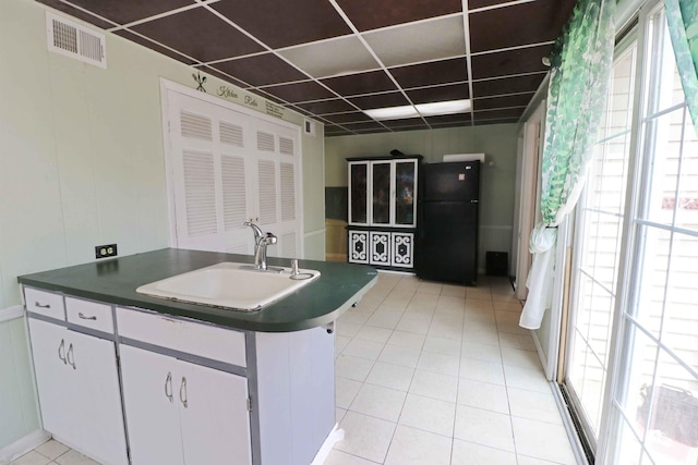 2907 Prairie Ln, Lafayette, IN 47904 - kitchen featuring freestanding refrigerator, a drop ceiling, dark countertops, light tile patterned floors, and white cabinets