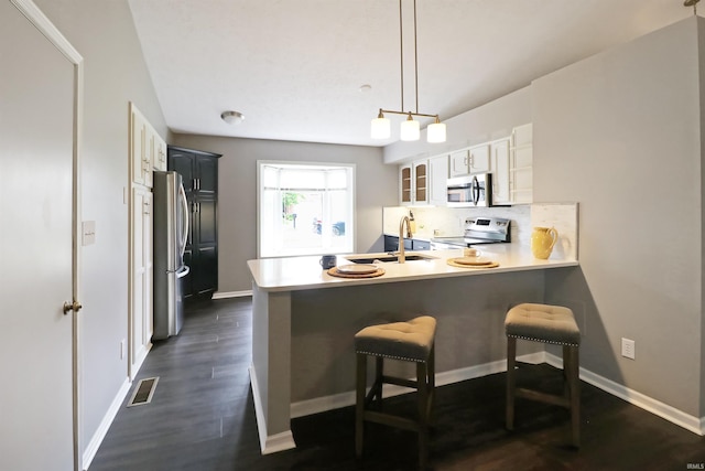 3847 Lodi Ln, Lafayette, IN 47905 - kitchen with stainless steel appliances, a peninsula, glass insert cabinets, a breakfast bar, and decorative backsplash
