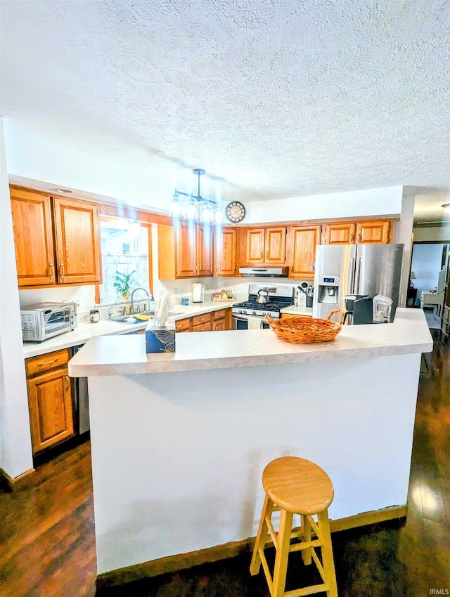 11497 N Biscayne Ln, Cromwell, IN 46732 - kitchen with stainless steel appliances, light countertops, under cabinet range hood, a textured ceiling, and dark wood-style flooring