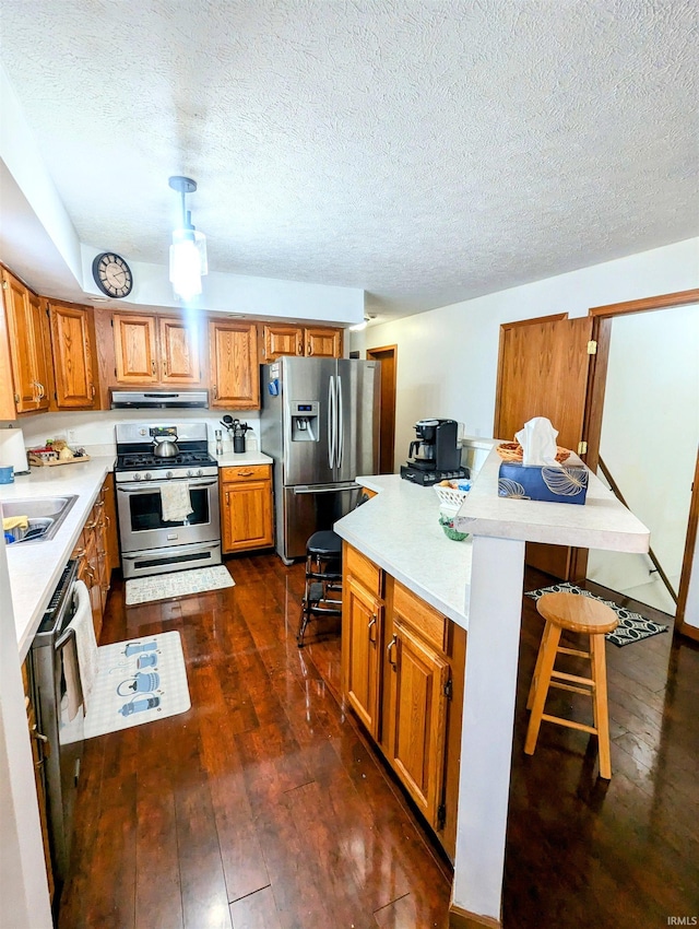 11497 N Biscayne Ln, Cromwell, IN 46732 - kitchen with stainless steel appliances, exhaust hood, brown cabinetry, a breakfast bar area, and a textured ceiling