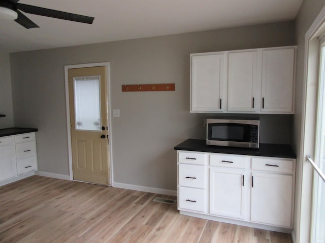 2305 Hillis Ct, Kokomo, IN 46902 - kitchen featuring stainless steel microwave, light wood finished floors, white cabinets, a ceiling fan, and dark countertops