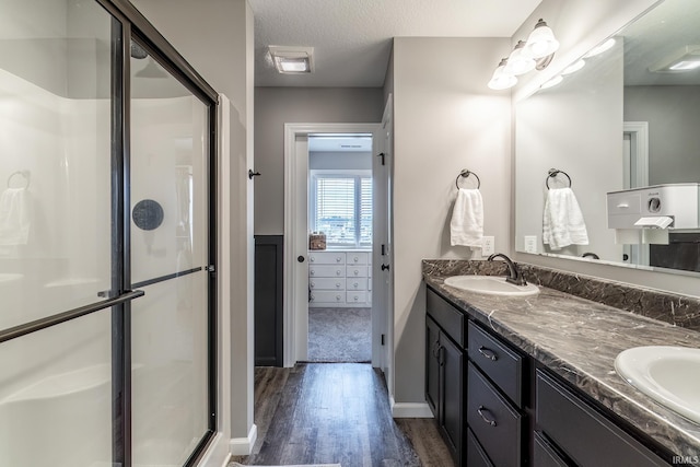 1492 Monte Carlo Dr, Huntertown, IN 46748 - bathroom featuring wood finished floors, a stall shower, double vanity, and a textured ceiling