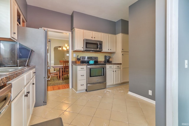 2736 Marion Ave, Evansville, IN 47712 - kitchen featuring appliances with stainless steel finishes, decorative backsplash, dark countertops, a chandelier, and white cabinetry