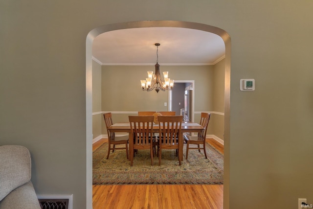 2736 Marion Ave, Evansville, IN 47712 - dining space with wood finished floors, crown molding, arched walkways, and a chandelier
