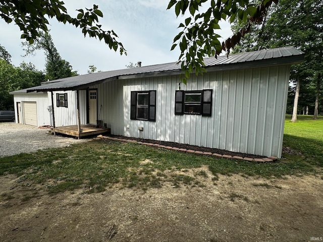 13687 E Ivan Ct, Bloomington, IN 47403 - view of front of house with board and batten siding, driveway, a metal roof, a garage, and a front lawn