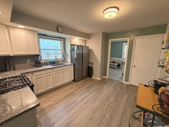 1814 S Douglas St, South Bend, IN 46613 - kitchen with freestanding refrigerator, white cabinets, light wood finished floors, gas range, and light stone countertops