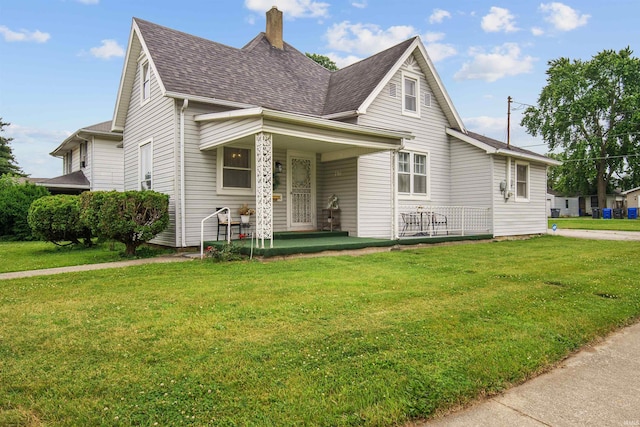 701 E N St, Kokomo, IN 46901 - view of front facade featuring a shingled roof, a front yard, a chimney, and covered porch