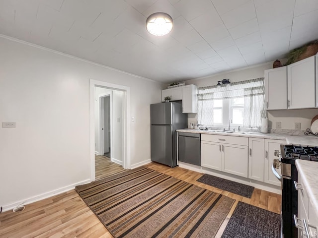 701 E N St, Kokomo, IN 46901 - kitchen featuring appliances with stainless steel finishes, light countertops, light wood-style flooring, crown molding, and white cabinets