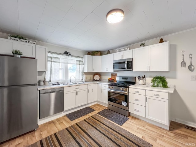 701 E N St, Kokomo, IN 46901 - kitchen with stainless steel appliances, light wood finished floors, light countertops, white cabinets, and crown molding