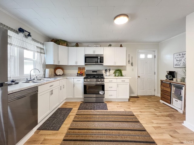701 E N St, Kokomo, IN 46901 - kitchen with stainless steel appliances, ornamental molding, white cabinetry, light wood-style flooring, and light countertops