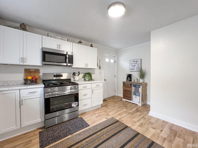 701 E N St, Kokomo, IN 46901 - kitchen featuring appliances with stainless steel finishes, light wood-type flooring, light countertops, white cabinets, and crown molding