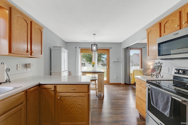 9536 Ballymore Dr, Fort Wayne, IN 46835 - kitchen featuring appliances with stainless steel finishes, dark wood-style floors, a peninsula, light countertops, and hanging light fixtures