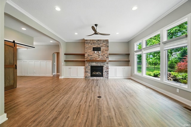 126 Tumbling Stone Ct, Fort Wayne, IN 46845 - unfurnished living room featuring ornamental molding, a ceiling fan, wood finished floors, a fireplace, and arched walkways