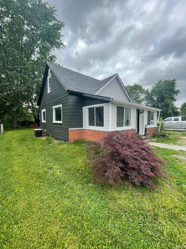 310 S Jefferson St, Bicknell, IN 47512 - view of home's exterior with brick siding, a shingled roof, and a lawn