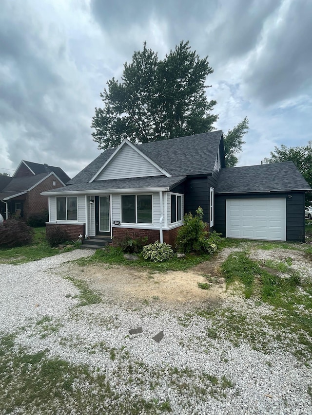 310 S Jefferson St, Bicknell, IN 47512 - ranch-style home featuring brick siding, gravel driveway, an attached garage, and a shingled roof