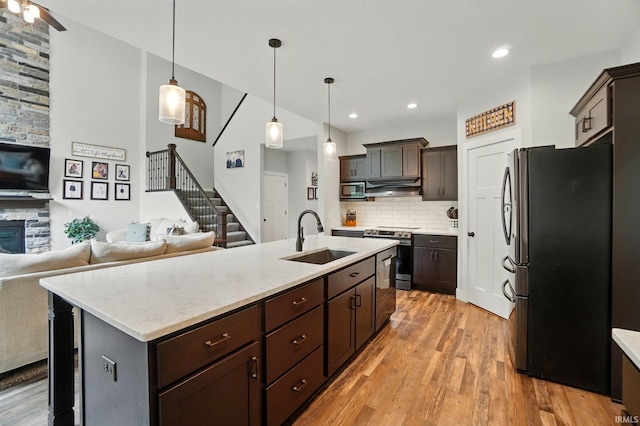 907 Switchfoot Dr, Huntertown, IN 46748 - kitchen featuring stainless steel appliances, under cabinet range hood, dark brown cabinets, decorative backsplash, and light wood finished floors
