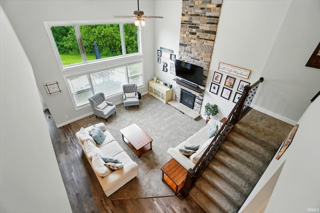 907 Switchfoot Dr, Huntertown, IN 46748 - living room with a stone fireplace, wood finished floors, ceiling fan, a towering ceiling, and stairs
