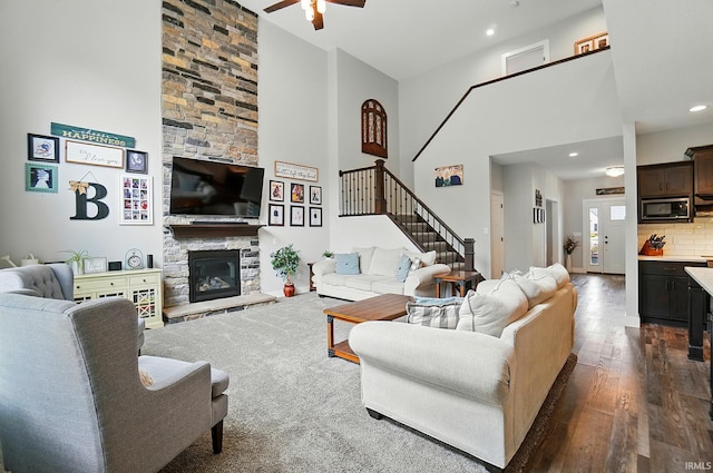 907 Switchfoot Dr, Huntertown, IN 46748 - living area with a high ceiling, a ceiling fan, stairs, dark wood-style flooring, and a fireplace