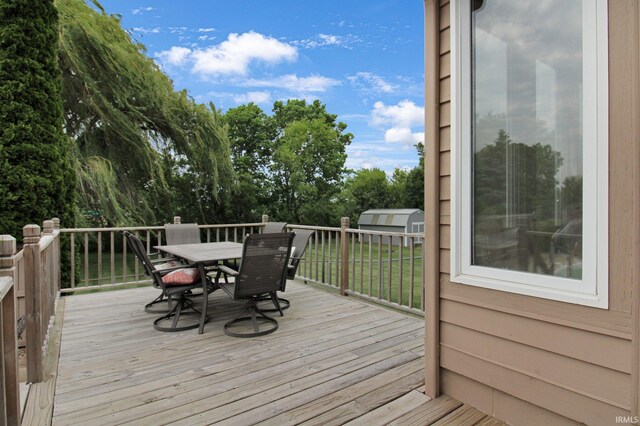 207 Meadows Dr, Greentown, IN 46936 - wooden terrace with a storage unit, outdoor dining space, and view of scattered trees