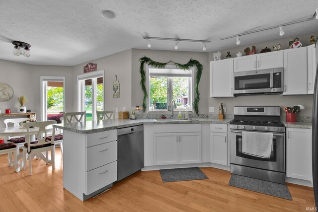 207 Meadows Dr, Greentown, IN 46936 - kitchen with appliances with stainless steel finishes, a peninsula, white cabinets, light wood-style flooring, and track lighting