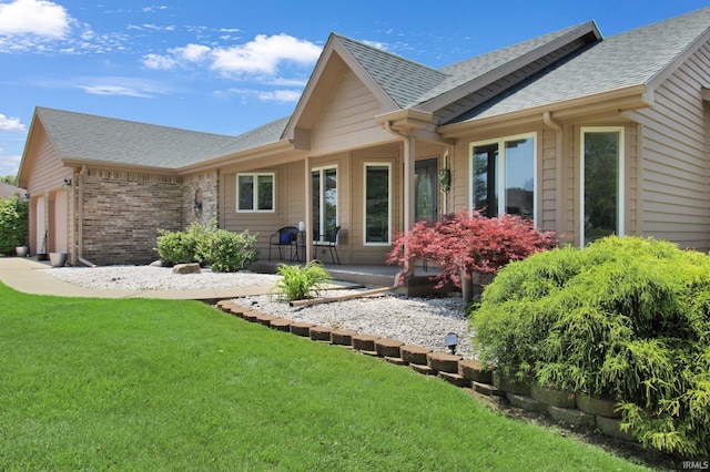 207 Meadows Dr, Greentown, IN 46936 - rear view of house featuring an attached garage, a shingled roof, a yard, and brick siding