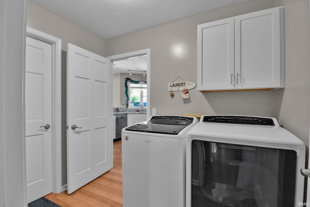 207 Meadows Dr, Greentown, IN 46936 - laundry room featuring cabinet space, washer and dryer, a textured ceiling, and light wood-type flooring
