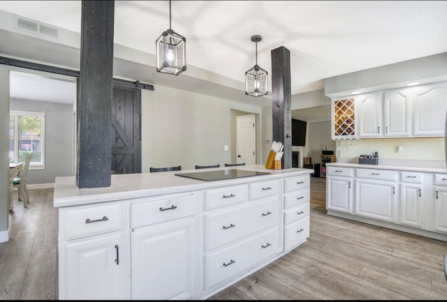 1006 Heather Rdg, Angola, IN 46703 - kitchen featuring a barn door, light wood-type flooring, black electric cooktop, light countertops, and decorative light fixtures