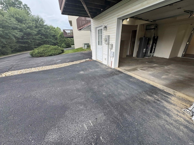 3832 E Cobble Creek Dr, Bloomington, IN 47401 - view of patio with water heater, a garage, and driveway