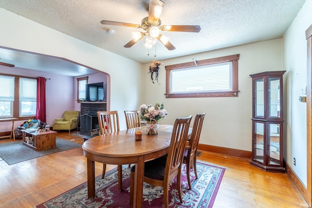 2130 N Wells St, Fort Wayne, IN 46808 - dining room featuring ceiling fan, a fireplace, light wood finished floors, and a textured ceiling