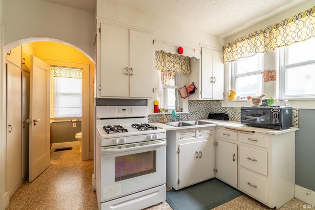 2130 N Wells St, Fort Wayne, IN 46808 - kitchen featuring gas range gas stove, black microwave, arched walkways, plenty of natural light, and a textured ceiling