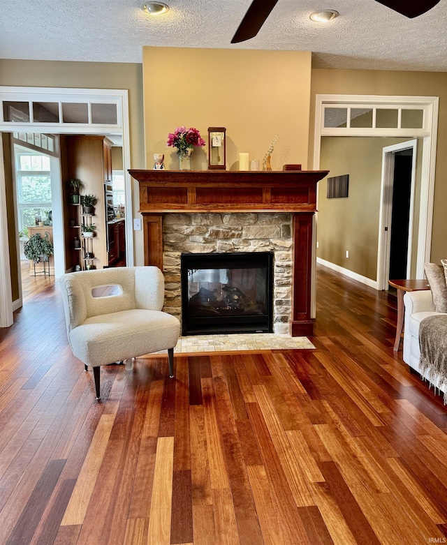 3638 Swansea Dr, West Lafayette, IN 47906 - living area featuring a ceiling fan, a textured ceiling, wood-type flooring, and a stone fireplace