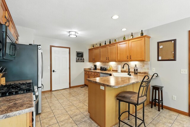 5432 Argiano Xing, Fort Wayne, IN 46845 - kitchen featuring black microwave, a peninsula, backsplash, stainless steel range with gas stovetop, and a breakfast bar