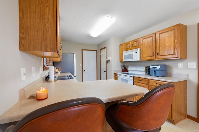 5371 Bear Creek Pass, Auburn, IN 46706 - kitchen featuring white appliances, light countertops, a peninsula, and brown cabinets