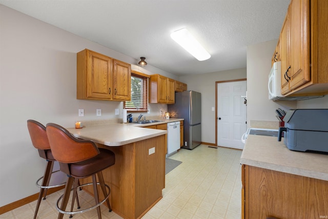 5371 Bear Creek Pass, Auburn, IN 46706 - kitchen featuring white appliances, a peninsula, a kitchen breakfast bar, light countertops, and brown cabinets