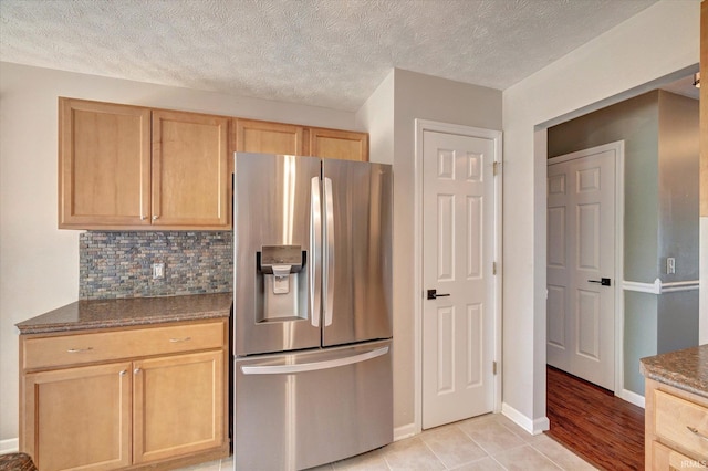 4539 N Shadow Wood Dr, Bloomington, IN 47404 - kitchen with stainless steel refrigerator with ice dispenser, light brown cabinetry, backsplash, dark stone counters, and a textured ceiling