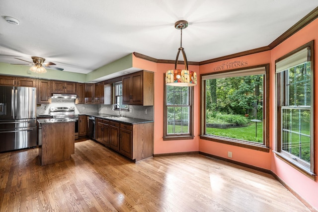 17112 Ridgefield Ct, Granger, IN 46530 - kitchen featuring appliances with stainless steel finishes, under cabinet range hood, tasteful backsplash, a center island, and ornamental molding