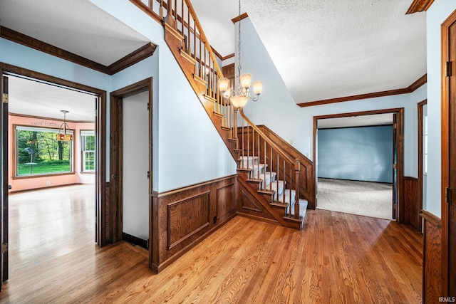 17112 Ridgefield Ct, Granger, IN 46530 - staircase featuring a chandelier, crown molding, wood finished floors, wainscoting, and a textured ceiling
