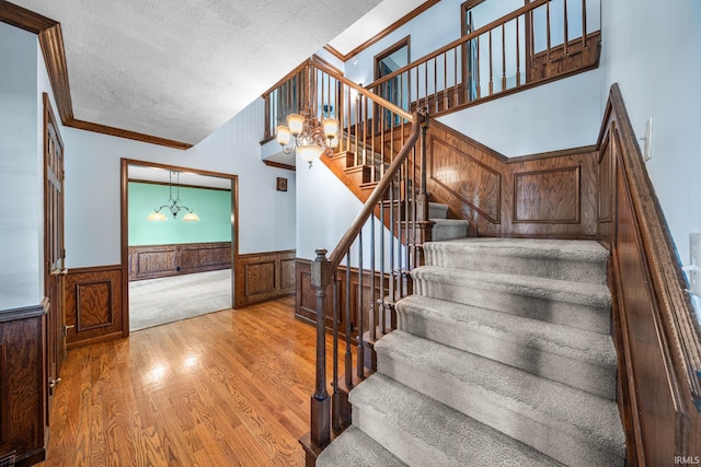 17112 Ridgefield Ct, Granger, IN 46530 - staircase with a chandelier, a wainscoted wall, wood finished floors, a textured ceiling, and ornamental molding