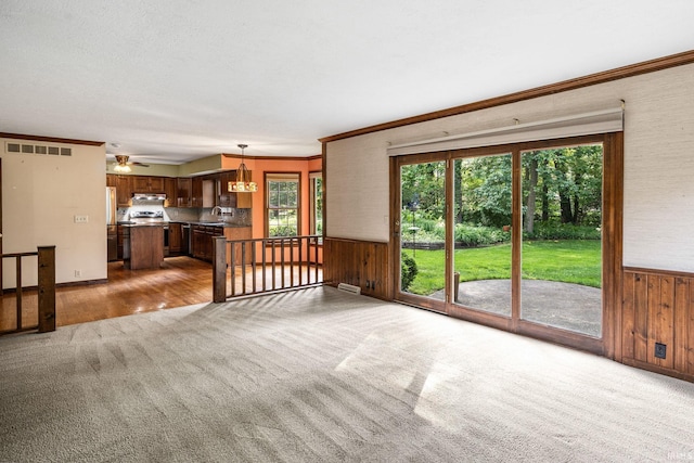 17112 Ridgefield Ct, Granger, IN 46530 - unfurnished living room with carpet floors, wood walls, wainscoting, ornamental molding, and a ceiling fan