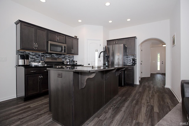 13710 Copper Strike Pass, Fort Wayne, IN 46845 - kitchen with appliances with stainless steel finishes, dark countertops, arched walkways, decorative backsplash, and dark wood-type flooring