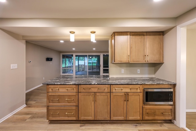 5219 Forest Grove Dr, Fort Wayne, IN 46835 - kitchen featuring stainless steel microwave, light wood-style floors, dark stone counters, brown cabinets, and recessed lighting