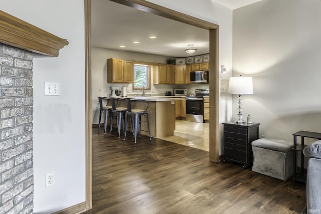 8005 Mackinac Cv, Fort Wayne, IN 46835 - kitchen featuring stainless steel appliances, dark wood finished floors, a kitchen bar, a peninsula, and light countertops