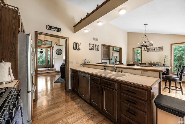 10880 Cougar Dr, Granger, IN 46530 - kitchen featuring stainless steel appliances, lofted ceiling, dark brown cabinetry, light wood-style flooring, and a peninsula